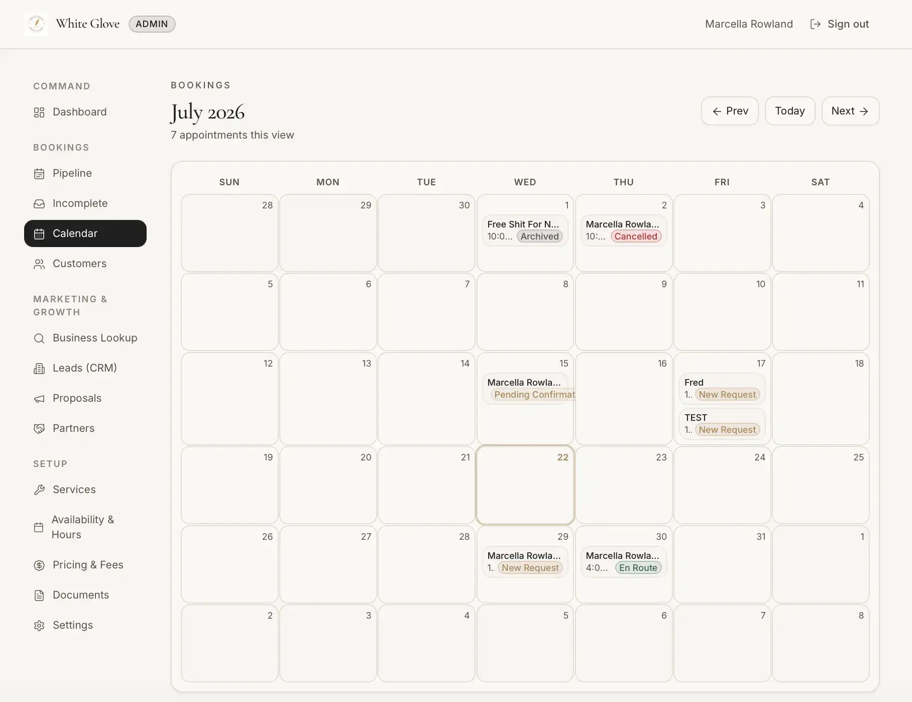 Admin bookings calendar for July 2026 showing appointments with status labels including Archived, Cancelled, New Request, Pending Confirmation, and En Route